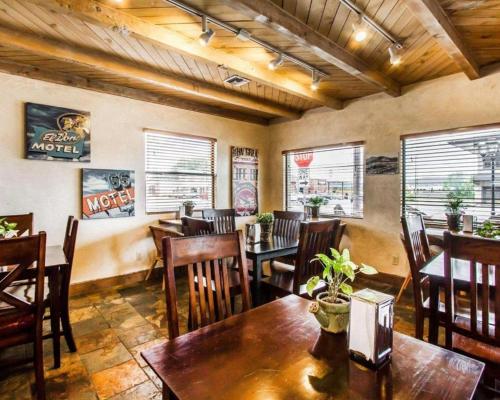 um restaurante com mesas e cadeiras de madeira e janelas em The Lodge on Route 66 em Williams