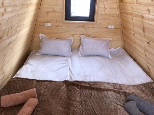 a bed in a wooden room with two pillows at Paradiso Mestia in Mestia