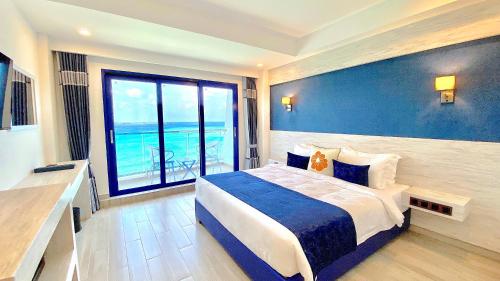 a bedroom with a large bed and a large window at Kaani Palm Beach in Maafushi