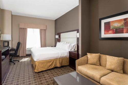 a hotel room with a bed and a couch at Holiday Inn Express & Suites Lantana, an IHG Hotel in Lantana