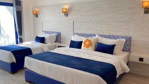 two beds in a hotel room with blue and white at Kaani Palm Beach in Maafushi
