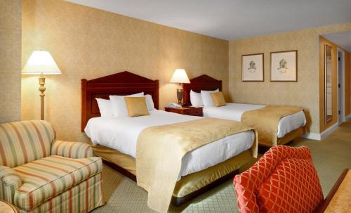 um quarto de hotel com duas camas e uma cadeira em Bally's Dover em Dover