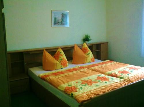 ein Bett mit gelben und orangefarbenen Kissen darauf in der Unterkunft Ferienwohnung Herpich in Ehrenberg