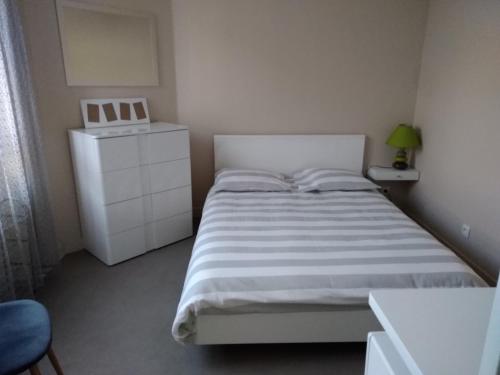 a white bedroom with a bed and a dresser at Le Clos Domenat 3 in Brive-la-Gaillarde