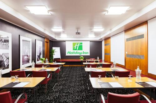 a restaurant with wooden tables and red chairs at Holiday Inn Milan Garibaldi Station by IHG in Milan