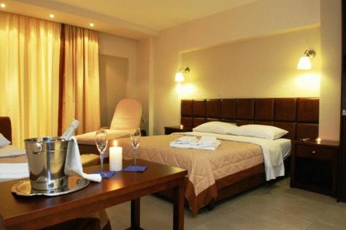 Habitación de hotel con cama y mesa con copas de vino en Hotel Ioanna, en Olympiakí Aktí