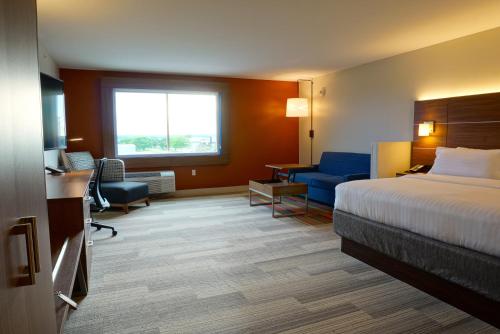 a hotel room with a bed and a living room at Holiday Inn Express & Suites Omaha - Millard Area by IHG in Millard