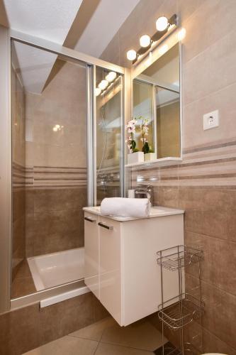 ein Badezimmer mit weißem Waschbecken und Dusche in der Unterkunft Apartman Luka in Igrane