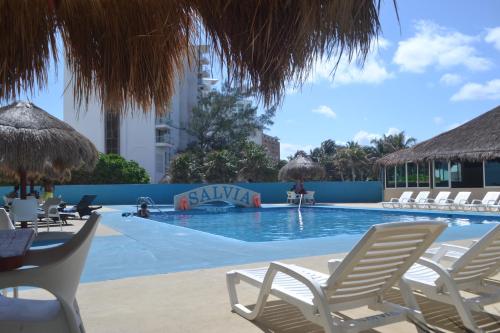 una piscina con tumbonas y sillas en Salvia Condominio, en Cancún