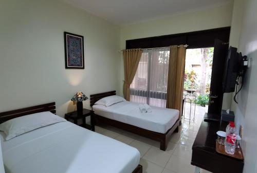 1 dormitorio con 2 camas y ventana en Puri Pangeran Hotel, en Yogyakarta