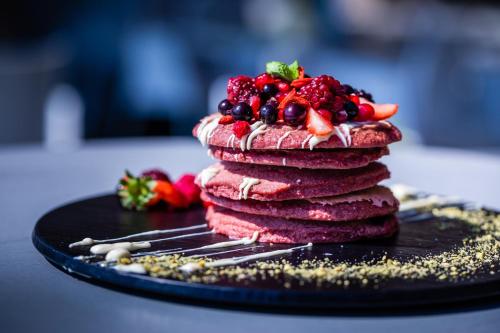 a stack of pancakes with berries on a black plate at Crowne Plaza Limassol, an IHG Hotel in Limassol