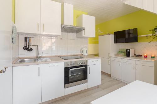 a white kitchen with white cabinets and a sink at Apartments Green Paradise in Bohinj