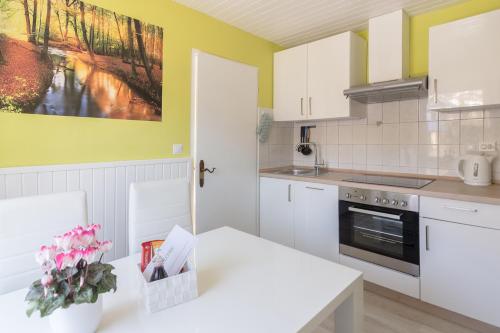 a kitchen with white cabinets and a white table at Apartments Green Paradise in Bohinj