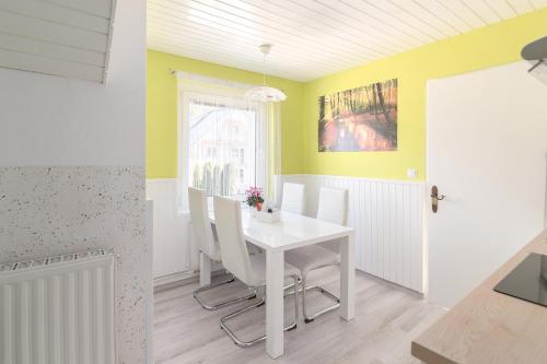 Apartments Green Paradise في بوينج: غرفة طعام مع طاولة بيضاء وكراسي