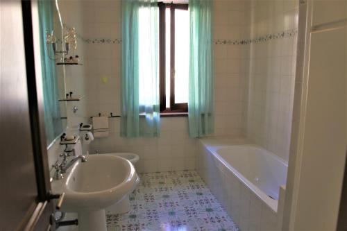 a bathroom with a tub and a sink and a bath tub at CLAUDIA VACANZA TOSCANA - Appartamento Nocciolo- 10 min da Siena in Malignano