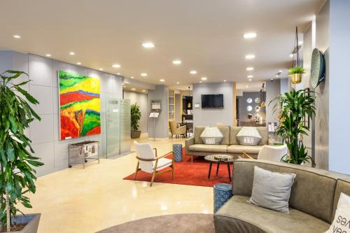a lobby with couches and chairs and a painting on the wall at Holiday Inn Milan Garibaldi Station by IHG in Milan