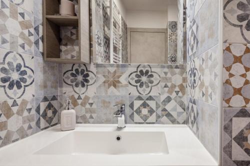 een witte wastafel in een badkamer met tegels bij Open the Classic Wooden Shutters at a Cozy City Nest in Florence