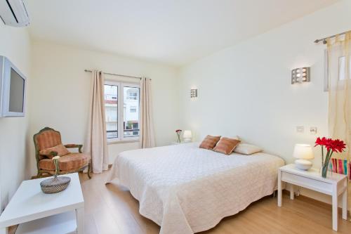1 dormitorio blanco con 1 cama y 1 silla en Dom Manuel, en Lagos