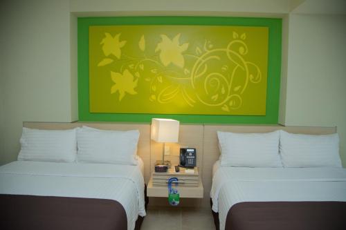 a room with two beds and a green painting at Holiday Inn Coatzacoalcos by IHG in Coatzacoalcos
