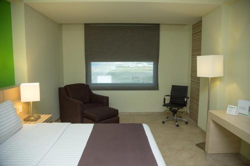 a hotel room with a bed and a chair at Holiday Inn Coatzacoalcos by IHG in Coatzacoalcos