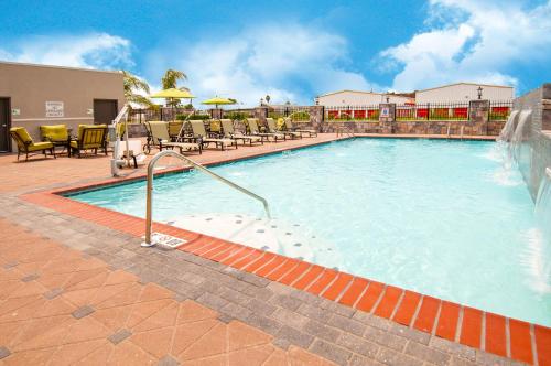 a large swimming pool with chairs and umbrellas at Holiday Inn - New Orleans Airport North by IHG in Kenner