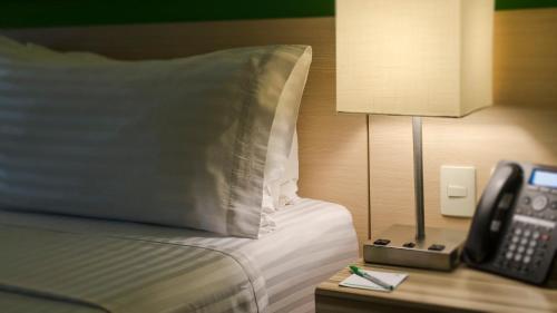 a hotel room with a bed with a lamp and a phone at Holiday Inn Coatzacoalcos by IHG in Coatzacoalcos