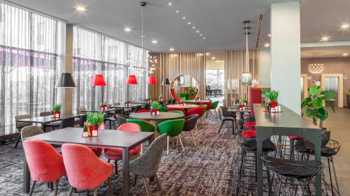 a restaurant with tables and chairs and red chairs at Holiday Inn Munich - Westpark, an IHG Hotel in Munich