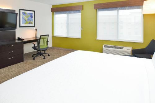 a room with a bed and a desk and a television at Holiday Inn Express Wixom by IHG in Wixom
