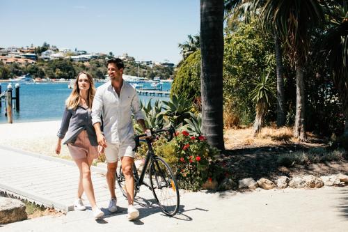 a man and a woman walking a bike on a sidewalk at Pier 21 Riverside Apartment Hotel in Fremantle