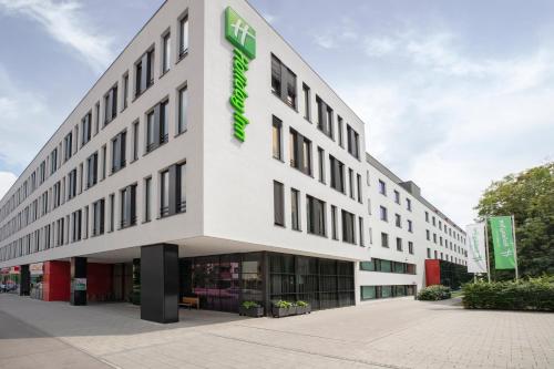 a large white building with a green sign on it at Holiday Inn Munich - Westpark by IHG in Munich