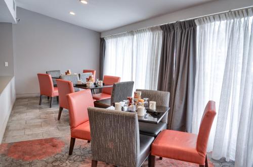 a dining room with tables and chairs and curtains at Holiday Inn Mobile West I-10 by IHG in Tillmans Corner