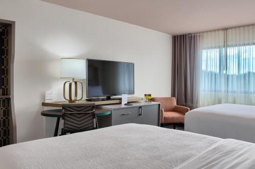 a hotel room with a bed and a tv and a desk at Holiday Inn Mobile West I-10 by IHG in Tillmans Corner