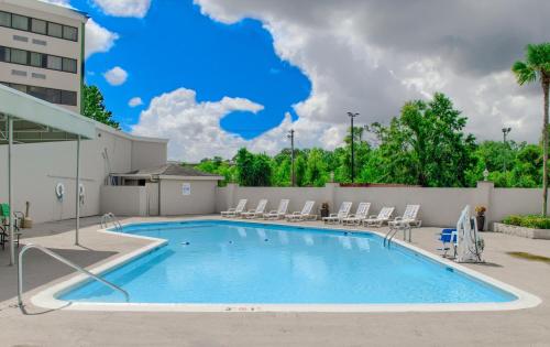 una piscina con sillas y un edificio en Holiday Inn Mobile West I-10, an IHG Hotel, en Tillmans Corner