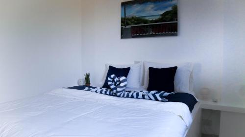 a white bed with blue and white pillows on it at Tablas Seaview Homestay in Ferrol