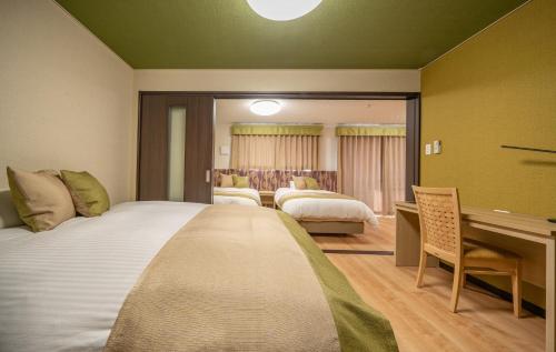 a hotel room with two beds and a desk at Residence Hotel Takayama Station in Takayama