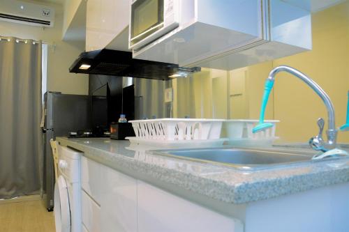 a kitchen with a sink and a microwave at Modern and Full Parquette Studio Springlake Summarecon Bekasi Apartment By Travelio in Bekasi
