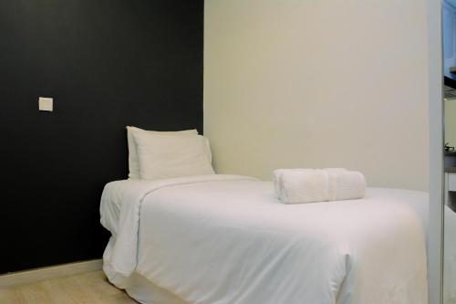 a white bed with two pillows on top of it at Modern and Full Parquette Studio Springlake Summarecon Bekasi Apartment By Travelio in Bekasi