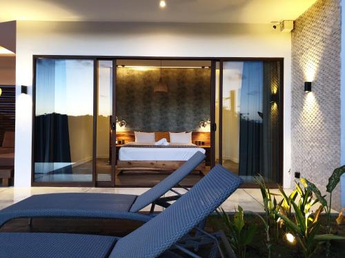 een slaapkamer met een bed en 2 stoelen op een patio bij Mango Tree Siargao in General Luna