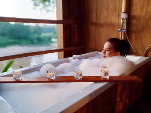 a woman is sitting in a bath tub at Nan De Panna Homestay in Nan