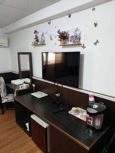 a room with a desk with a television on the wall at Chihpen Hot Spring Hotel in Wenquan