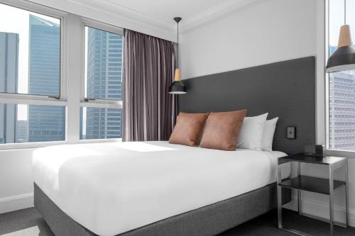 a bedroom with a large white bed and windows at Mantra on Kent in Sydney