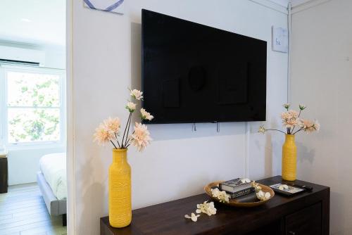 two yellow vases with flowers on a table in a room at Lotus Stay Manly - Apartment 31F in Sydney