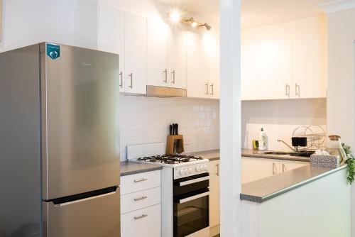a kitchen with white cabinets and a stainless steel refrigerator at Lotus Stay Manly - Apartment 31F in Sydney
