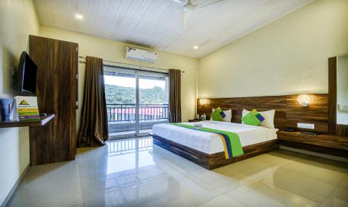 a bedroom with a bed and a large window at Treebo JP Cottage in Mahabaleshwar