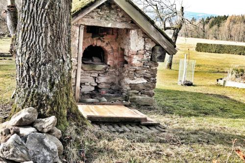 a stone oven sitting next to a tree at Dřevěný prázdninový domek SUNRISE in Stará Huť