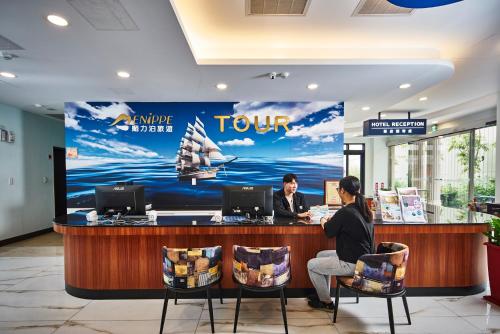 two people sitting at a counter in a hotel lobby at Menippe Hotel Kaohsiung in Kaohsiung