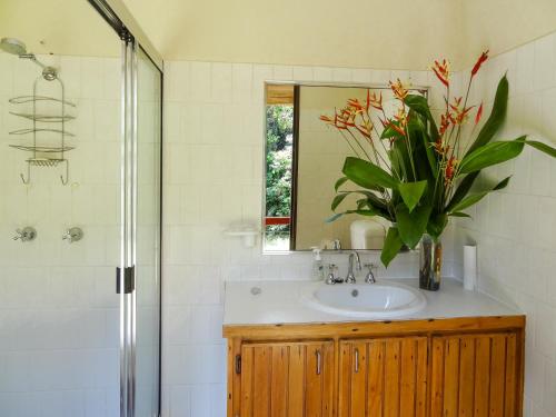 ein Badezimmer mit einem Waschbecken und einer Vase aus Blumen in der Unterkunft Noah Creek Eco Huts in Cape Tribulation