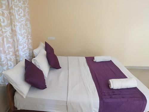 COFFEE NEST COORG في Somvārpet: غرفة نوم مع سرير مع الوسائد الأرجوانية والأبيض