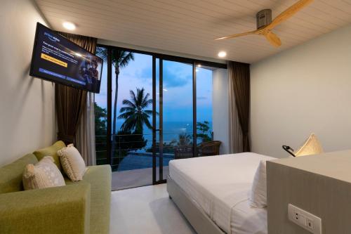 a bedroom with a tv and a bed and a couch at Kapuhala Koh Samui- Vegan Boutique Hotel in Chaweng Noi Beach