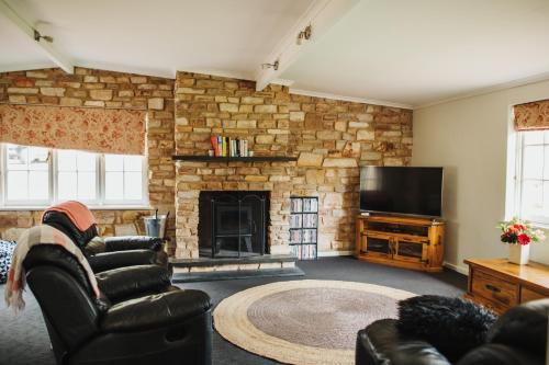 a living room with a stone fireplace and a television at Cooke Cottage in Clare